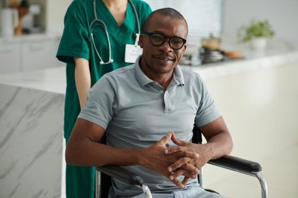 portrait-smiling-black-man-with-disability-having-social-worker-visiting-him-home_274689-45881